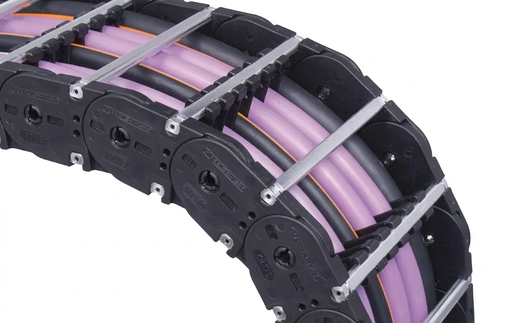 Black cable carrier with purple and black cables, partly visible, on a grey background
