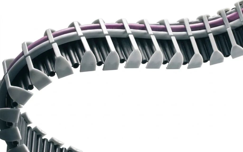 Grey-white cable carrier with purple and black cables, curved against a light background